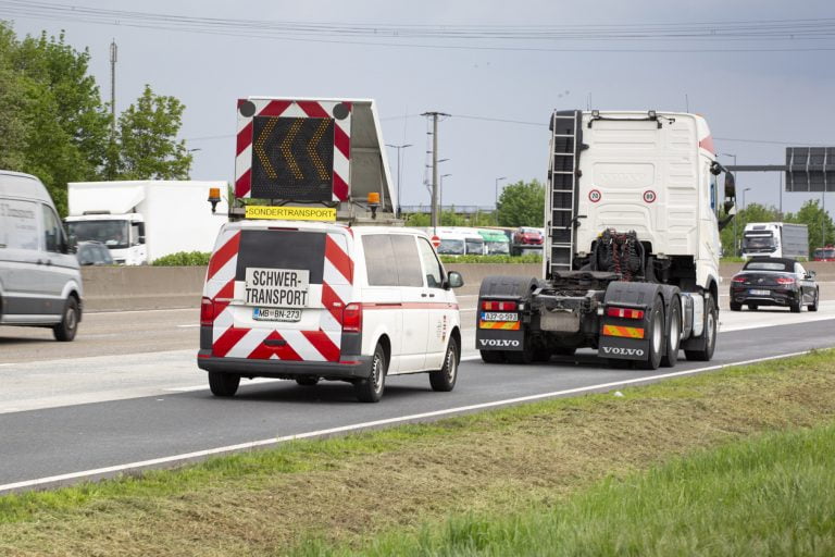 Begleitfahrzeug mit Schwertransport-Schild begleitet einen Schwertransport